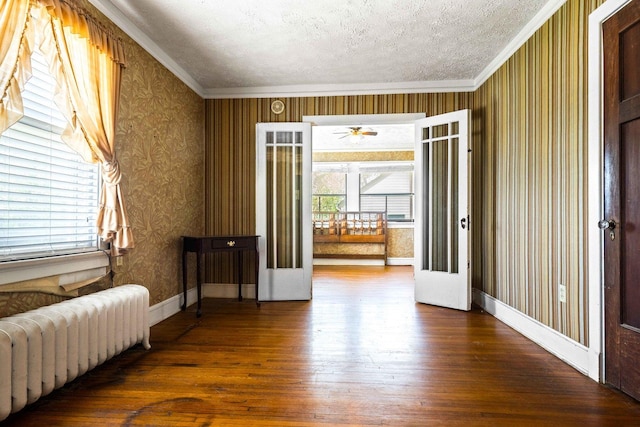 546 Elmwood Ct, El Paso, IL 61738 - unfurnished room with radiator, wallpapered walls, ornamental molding, hardwood / wood-style flooring, and a textured ceiling