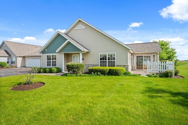 view of front of home with stone siding, a front lawn, a garage, and driveway