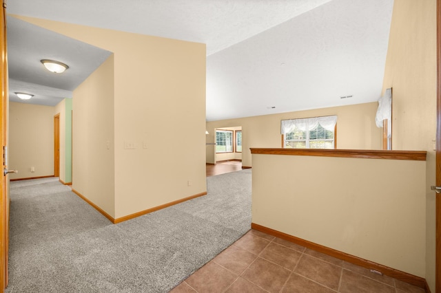 hallway featuring baseboards, carpet, an upstairs landing, and tile patterned floors