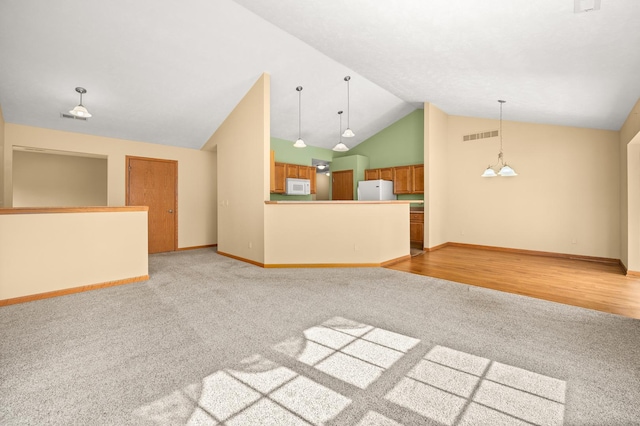 unfurnished living room featuring light colored carpet, baseboards, and high vaulted ceiling
