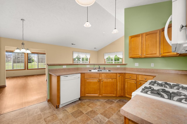 kitchen featuring white appliances, a sink, light countertops, a peninsula, and hanging light fixtures