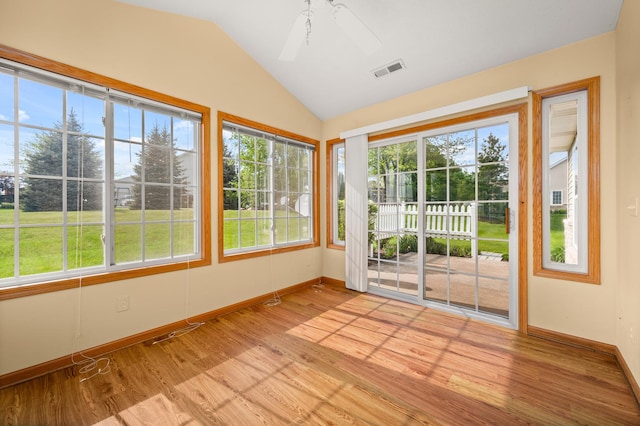 unfurnished sunroom featuring vaulted ceiling, plenty of natural light, baseboards, and wood finished floors