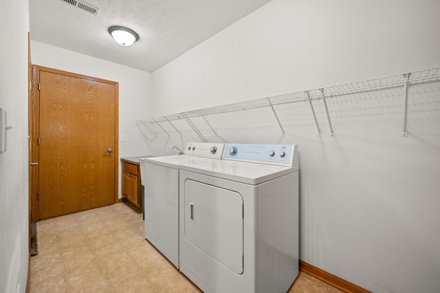 washroom featuring independent washer and dryer, cabinet space, and a textured ceiling