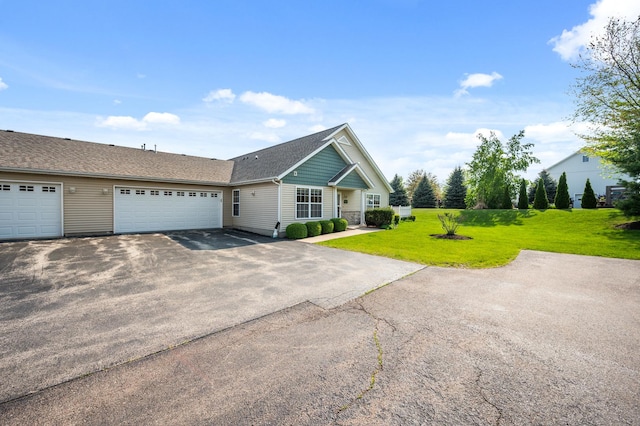 ranch-style house featuring driveway, a garage, a front lawn, and roof with shingles