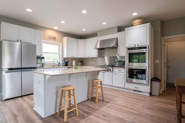 14445 W Walden Ln, Wadsworth, IL 60083 - kitchen with stainless steel appliances, wall chimney range hood, white cabinets, a center island, and recessed lighting