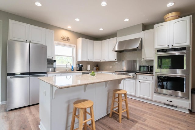 14445 W Walden Ln, Wadsworth, IL 60083 - kitchen featuring appliances with stainless steel finishes, wall chimney range hood, a sink, white cabinets, and a kitchen island