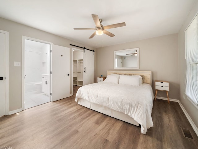1150 Jerald Dr, Joliet, IL 60431 - bedroom with a barn door, wood finished floors, baseboards, ensuite bathroom, and a ceiling fan