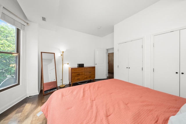 bedroom with dark wood-style flooring, multiple closets, and baseboards
