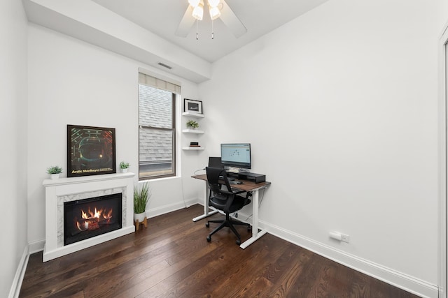 office space with baseboards, wood finished floors, a fireplace, and ceiling fan