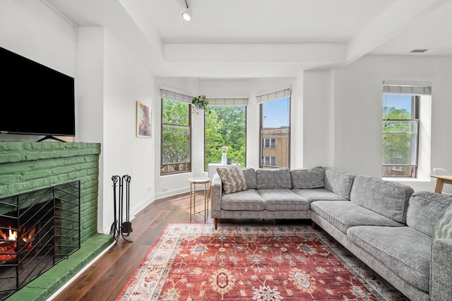 living room with healthy amount of natural light, dark wood finished floors, a brick fireplace, and baseboards