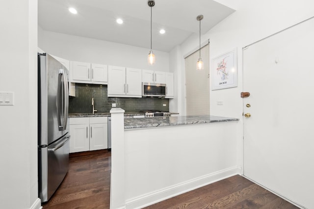 kitchen featuring appliances with stainless steel finishes, stone counters, dark wood-type flooring, a peninsula, and backsplash