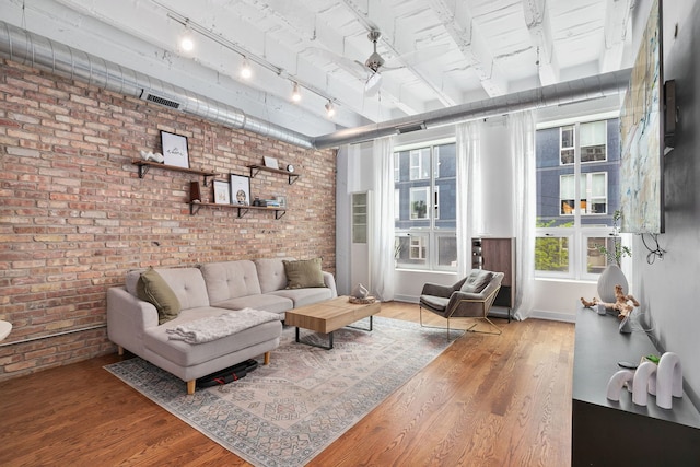 living area with brick wall, wood finished floors, and track lighting