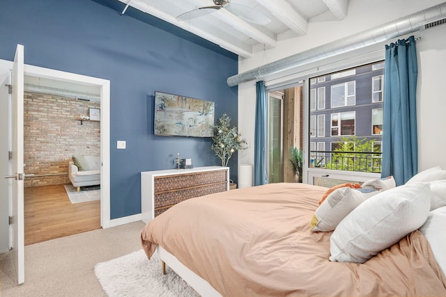bedroom featuring beam ceiling, brick wall, and carpet