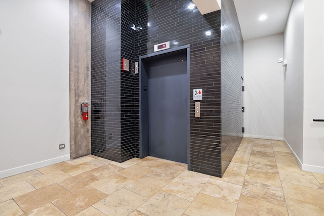 elevator featuring baseboards and a fire extinguisher