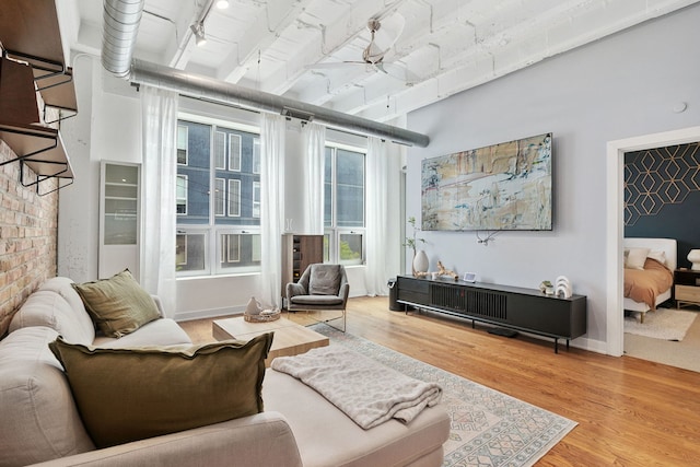 living area with wood finished floors, ceiling fan, and a towering ceiling