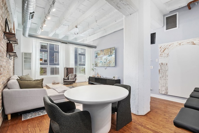 living room with wood finished floors, rail lighting, a towering ceiling, and baseboards