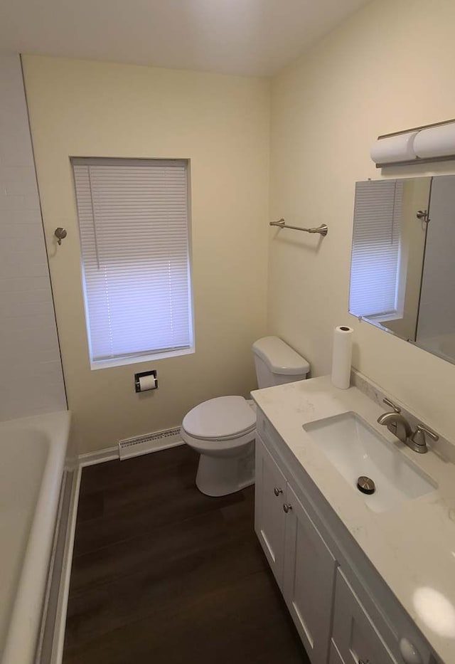 full bath with toilet, vanity, wood finished floors, and a bath