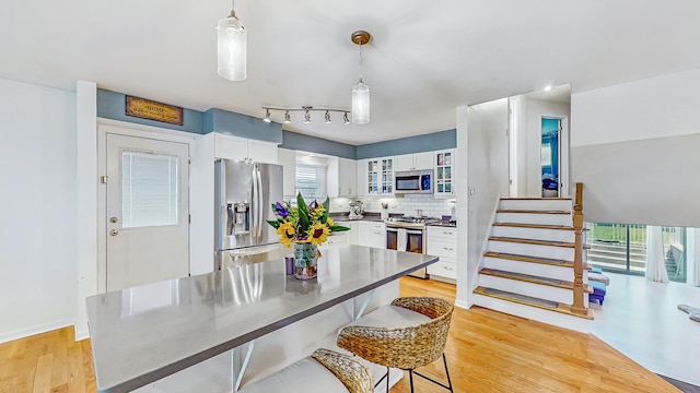 9405 Morgan Ave, Evanston, IL 60203 - kitchen featuring stainless steel appliances, light wood-type flooring, white cabinets, backsplash, and glass insert cabinets