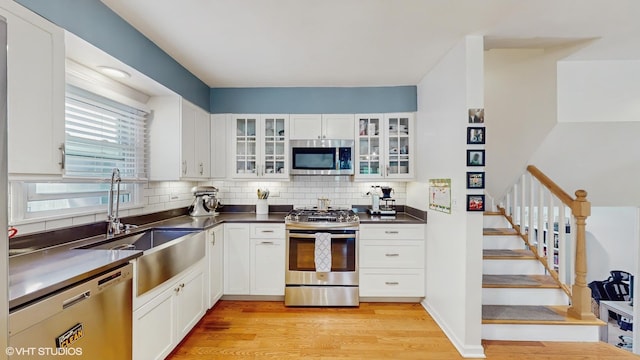 9405 Morgan Ave, Evanston, IL 60203 - kitchen with appliances with stainless steel finishes, light wood-style floors, white cabinetry, and tasteful backsplash