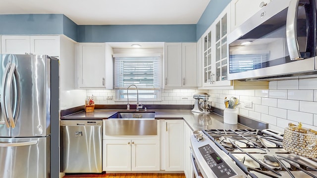 9405 Morgan Ave, Evanston, IL 60203 - kitchen with stainless steel appliances, a sink, white cabinetry, decorative backsplash, and dark countertops