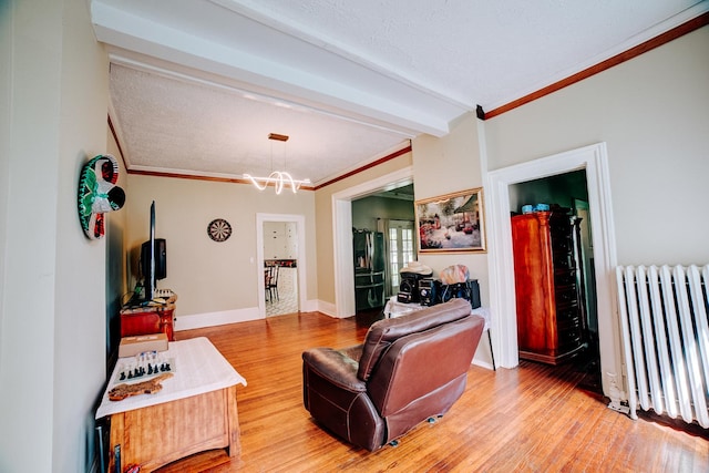 407 E Mulberry St, Watseka, IL 60970 - living area featuring radiator, wood finished floors, beam ceiling, a chandelier, and crown molding