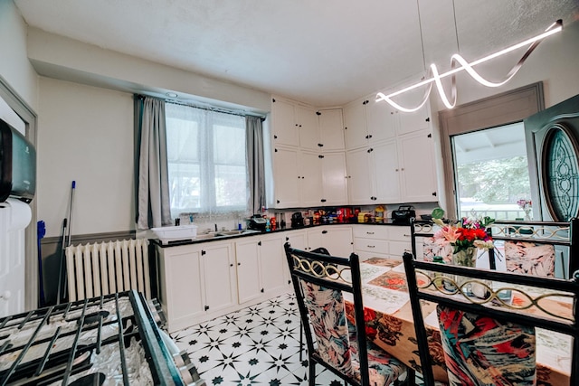 407 E Mulberry St, Watseka, IL 60970 - kitchen featuring radiator heating unit, plenty of natural light, and white cabinetry