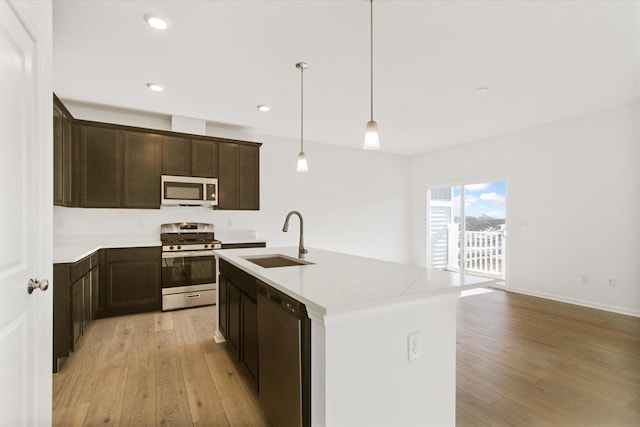 kitchen featuring a sink, appliances with stainless steel finishes, light wood-style flooring, dark brown cabinets, and recessed lighting