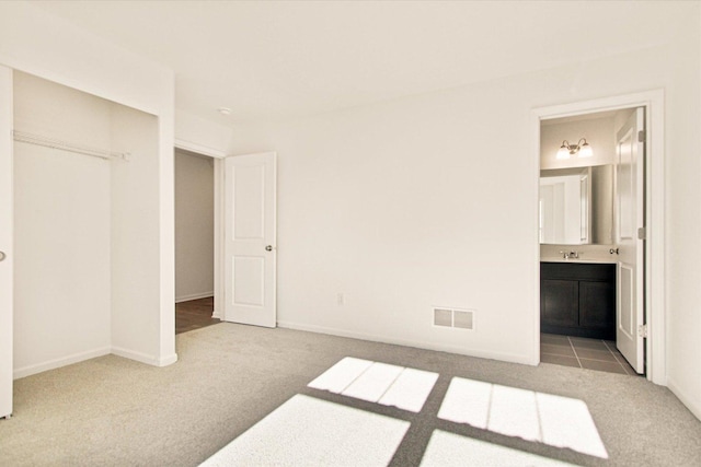 unfurnished bedroom with carpet floors, ensuite bath, a closet, and baseboards