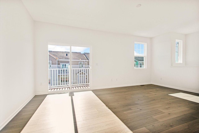 spare room featuring dark wood-style floors and baseboards