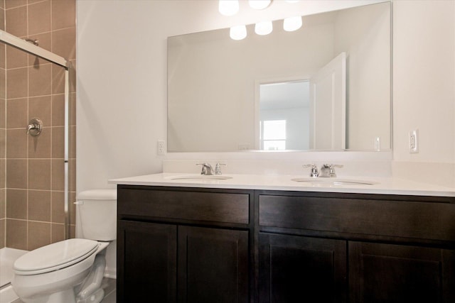 bathroom with toilet, double vanity, and tiled shower