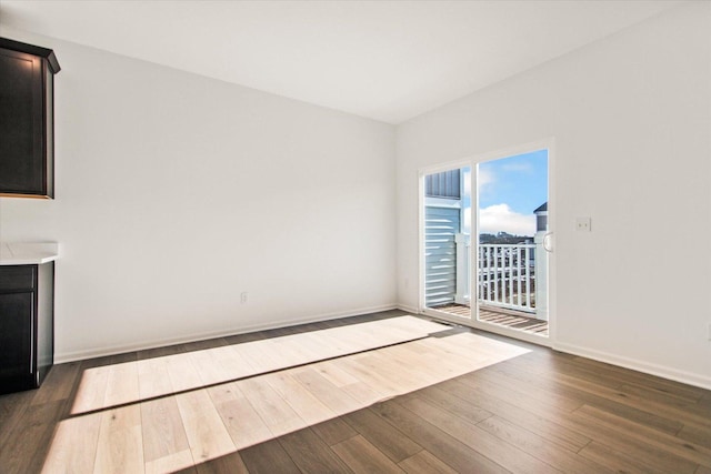unfurnished living room with dark wood-type flooring and baseboards