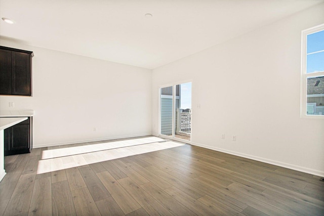 unfurnished living room with plenty of natural light, wood finished floors, and baseboards