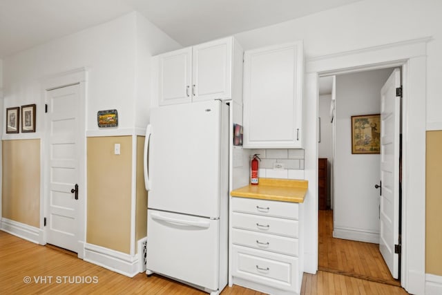 7223 Jackson Blvd, Forest Park, IL 60130 - kitchen featuring freestanding refrigerator, white cabinetry, light wood-style flooring, decorative backsplash, and light countertops