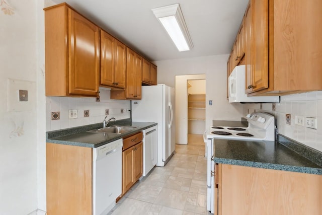 kitchen with white appliances, a sink, dark countertops, and tasteful backsplash
