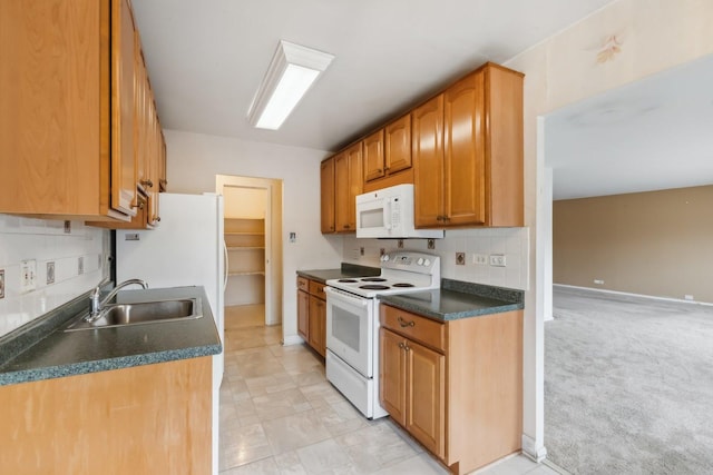 kitchen featuring white appliances, a sink, backsplash, and dark countertops