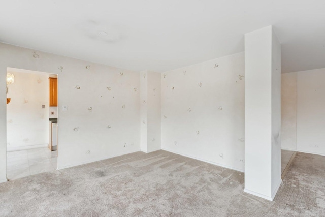 unfurnished room with light colored carpet and baseboards