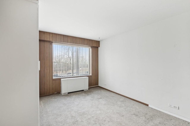 empty room with radiator, light carpet, and baseboards