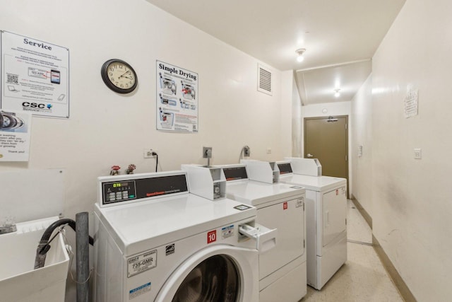 communal laundry room with washing machine and dryer and baseboards