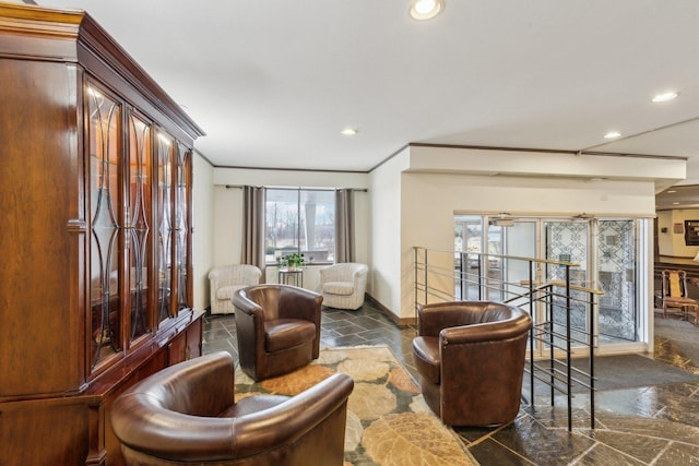 sitting room featuring stone tile flooring, an upstairs landing, recessed lighting, baseboards, and ornamental molding