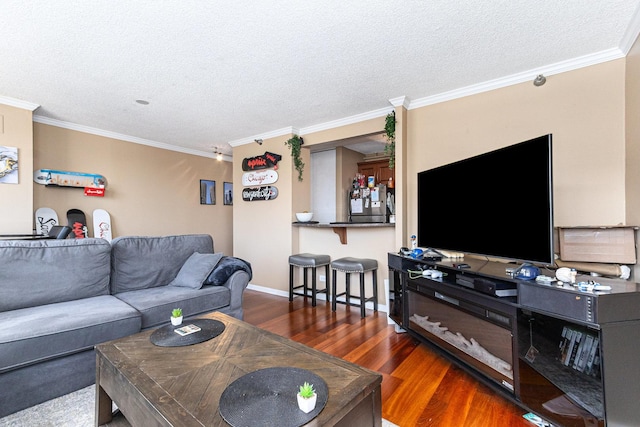 living room featuring wood finished floors, a textured ceiling, ornamental molding, and baseboards