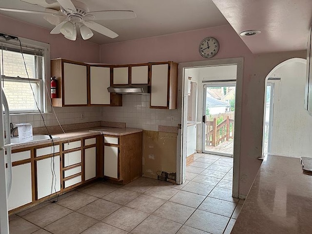 3010 N Nottingham Ave, Chicago, IL 60634 - kitchen featuring under cabinet range hood, arched walkways, backsplash, a ceiling fan, and light tile patterned floors