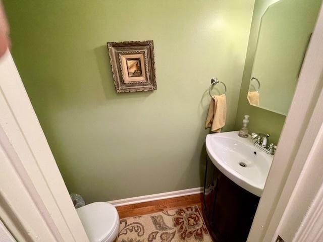 bathroom with vanity, baseboards, wood finished floors, and toilet
