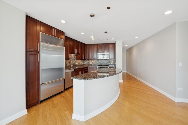 60 E Monroe St Unit 3007, Chicago, IL 60603 - kitchen with appliances with stainless steel finishes, light wood-style floors, dark stone countertops, tasteful backsplash, and decorative light fixtures