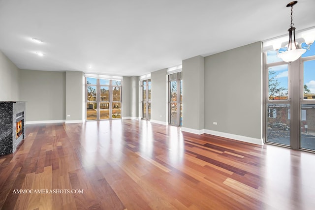 520 S Washington St Unit 201, Naperville, IL 60540 - unfurnished living room with plenty of natural light, expansive windows, wood finished floors, a glass covered fireplace, and baseboards