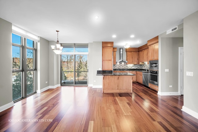 520 S Washington St Unit 201, Naperville, IL 60540 - kitchen with stainless steel appliances, wall chimney range hood, a chandelier, dark countertops, and wood finished floors