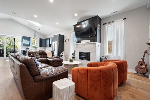 7929 N Octavia Ave, Niles, IL 60714 - living room with vaulted ceiling, recessed lighting, light wood-style flooring, a tiled fireplace, and a skylight