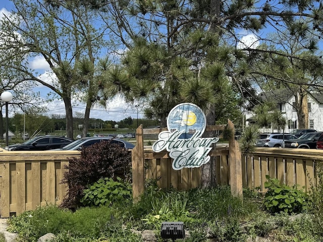 community / neighborhood sign with fence and uncovered parking