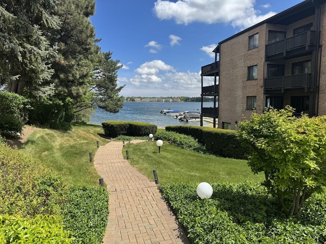 view of property's community with a water view and a lawn