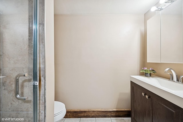 full bathroom featuring vanity, a shower stall, toilet, tile patterned flooring, and baseboards
