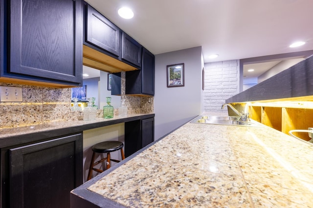 502 Deerpath St, Tolono, IL 61880 - kitchen featuring a sink, tasteful backsplash, light countertops, and a kitchen bar